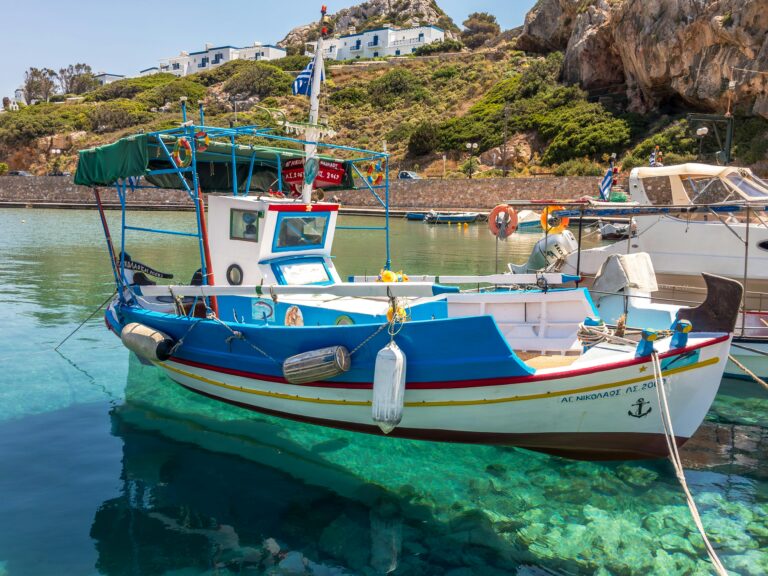 Colorful fishing boat in Syros, Greece. Clear waters under a vibrant blue sky.