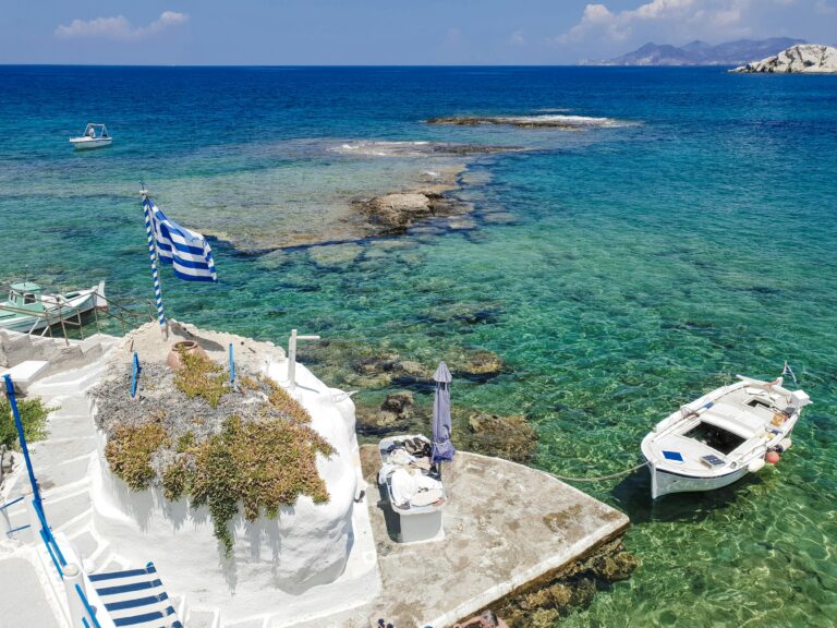 Stunning view of a Greek island with clear waters, boats, and traditional architecture.