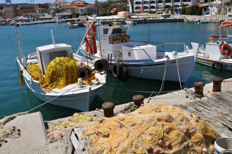 Colorful fishing boats with nets docked at a serene seaside pier.